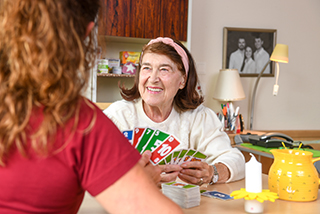 Bewohnerin und Pflegerin spielen zusammen ein Kartenspiel