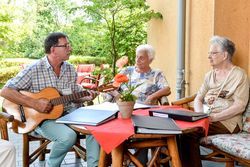 Sozialer Dienst spielt mit der Gitarre Lieder für die Bewohner 
