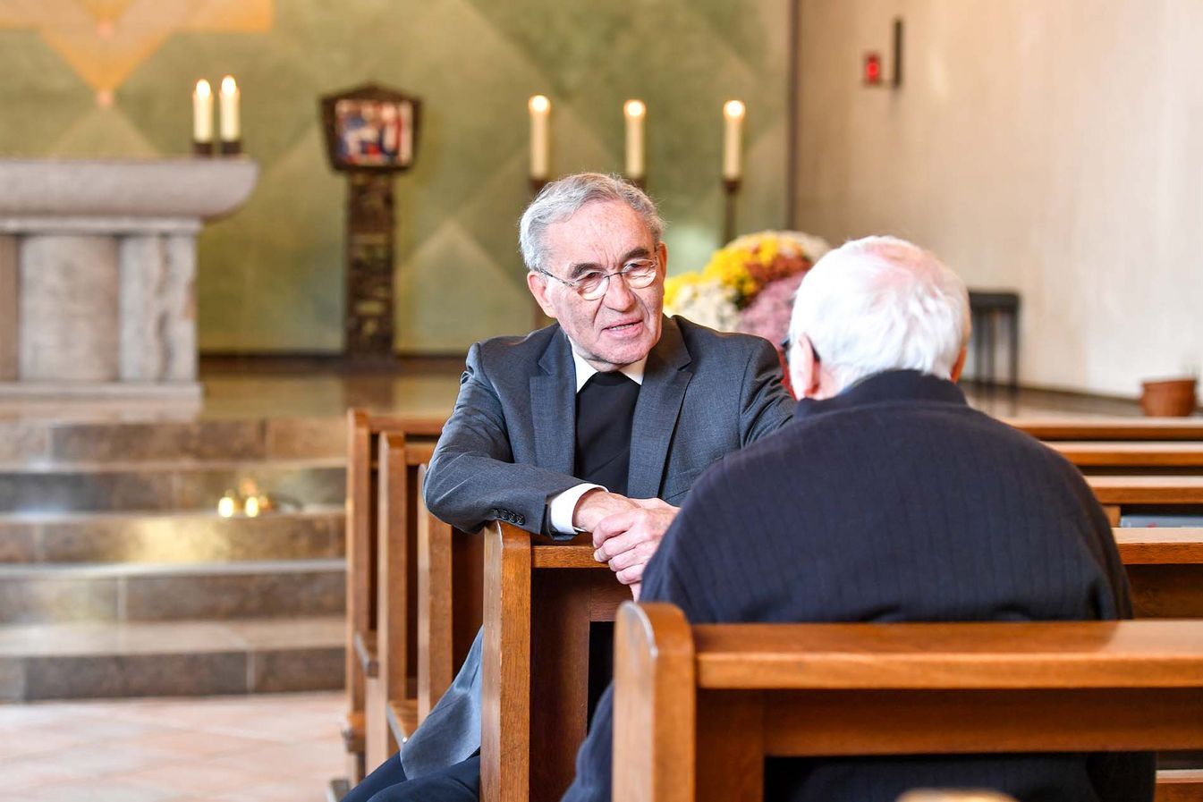 Seelsorger und Bewohner führen ein vertrautes Gespräch in der Kapelle