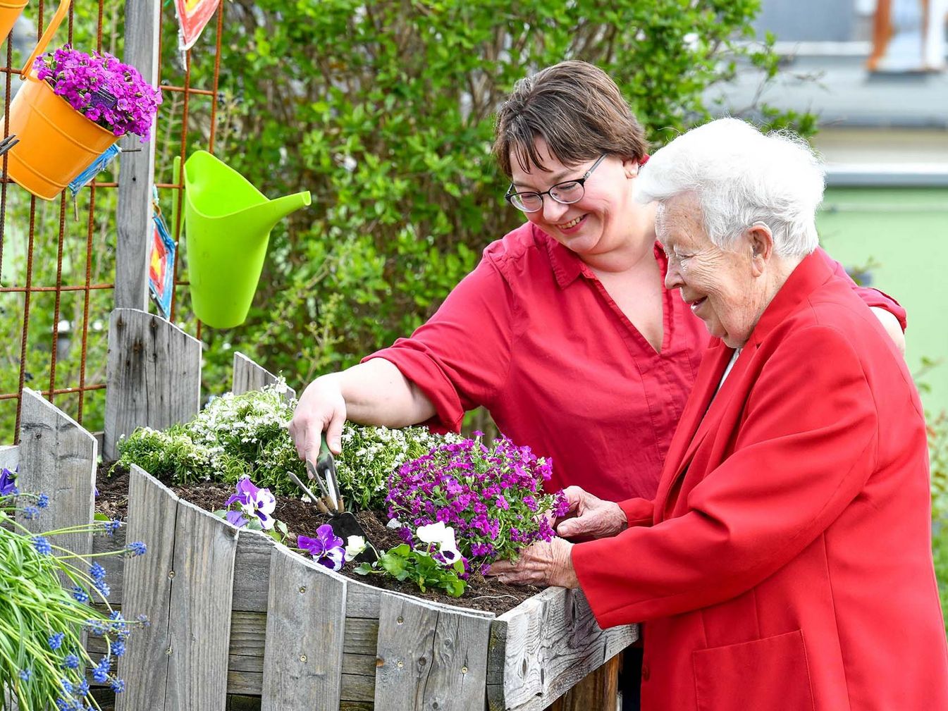 Pflegerin und Bewohnerin legen zusammen ein Blumenbeet an